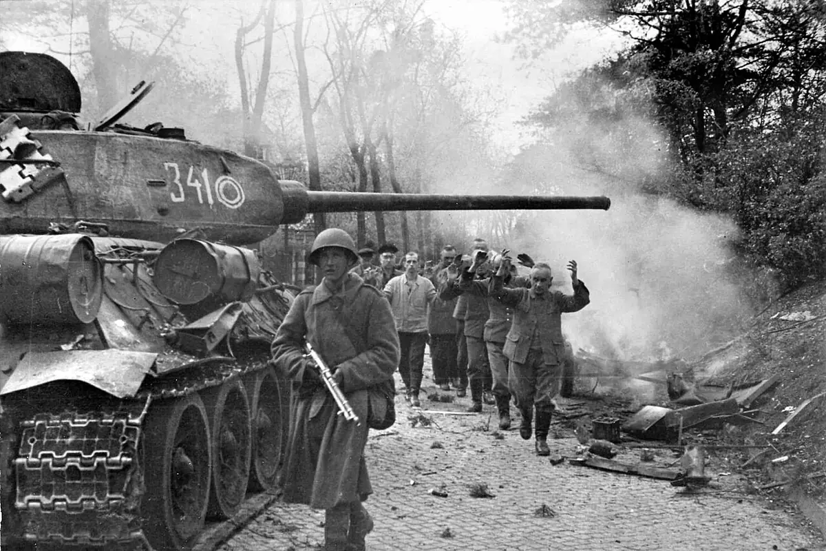 Танк Т-34-85 из 7-го гвардейского танкового корпуса и пленные ополченцы из фольксштурма на улицах Берлина